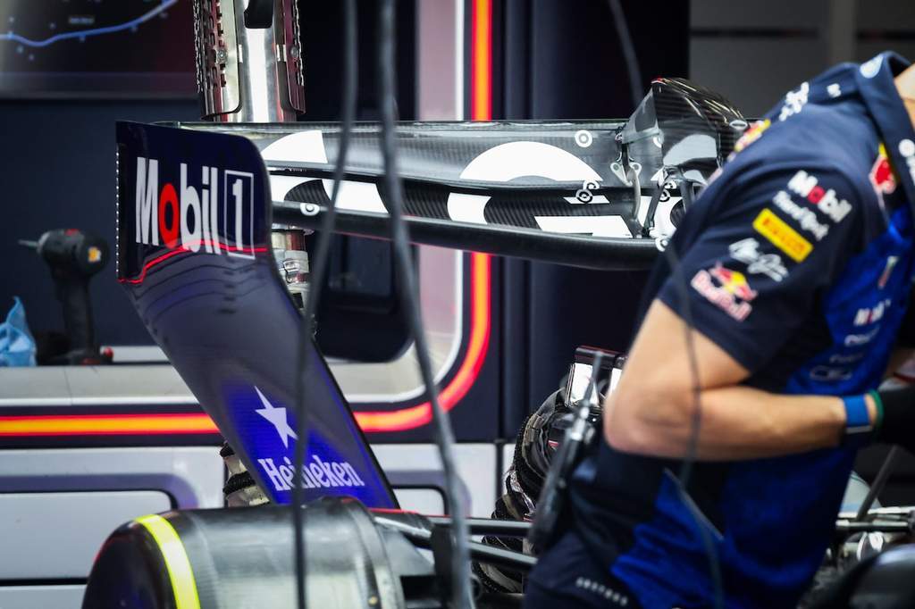 Mobil balap Formula 1 RB22 milik tim Red Bull Racing sedang dipersiapkan oleh mekanik di dalam garasi Sirkuit Spa-Francorchamps, menampilkan detail sayap belakang spesifikasi lama.