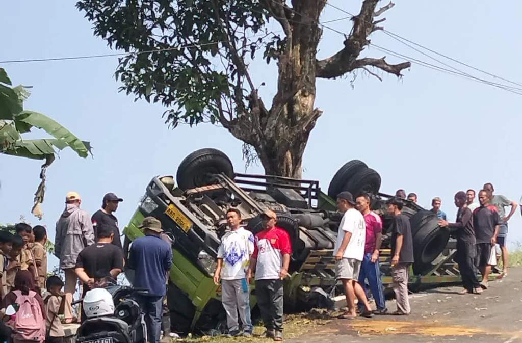 Kondisi truk Hino bermuatan material bangunan yang terguling dan terperosok ke dalam selokan di bahu Jalan Raya Cisandaan, Kecamatan Pamulihan, Kabupaten Garut.